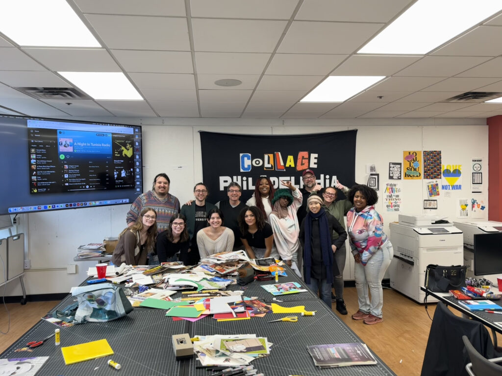 A group of people standing behind a table cluttered with paper and collage materials